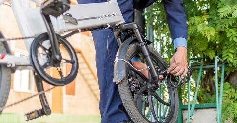 Zakenman in pak doet een extra slot om het wiel van zijn e-bike